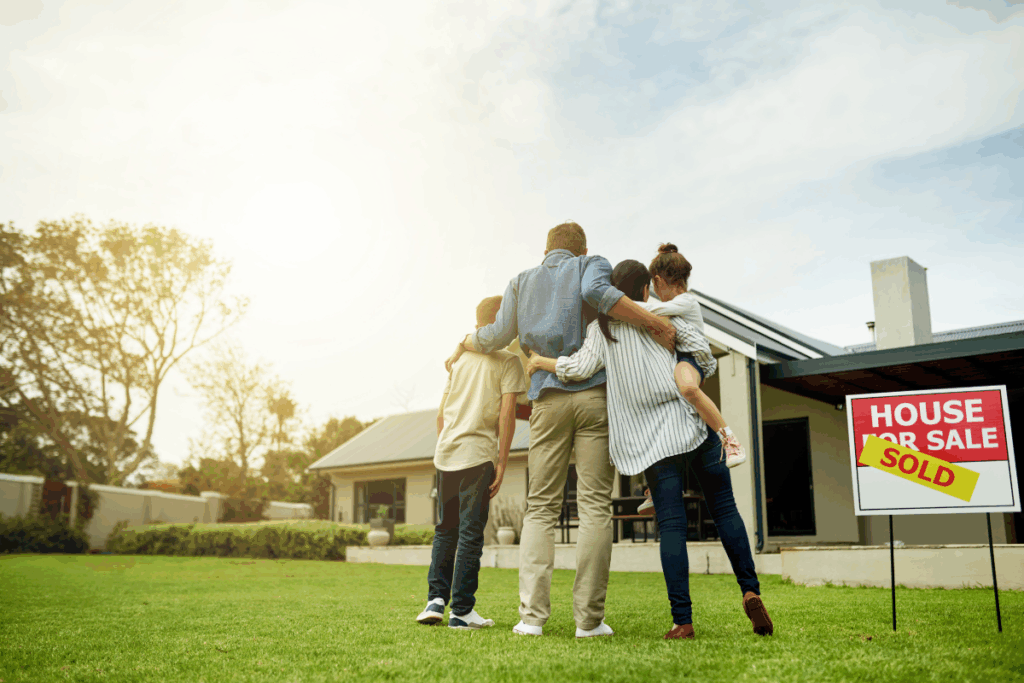 Adult children standing in front of parent’s estate home that has been sold